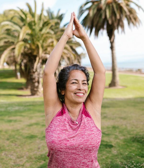 Senior woman smiling while doing a gentle yoga stretch.